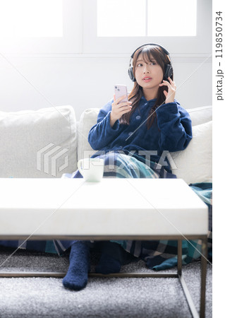 ヘッドフォンをつけて音楽を聴く歌う若い女性の全身のイメージ コピースペース ヘッドフォンをつけて音楽を聴く歌う若い女性の全身のイメージ コピースペース 119850734