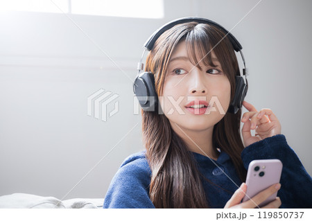 ヘッドフォンをつけて音楽を聴く歌う若い女性のクローズアップのイメージ コピースペースあり ヘッドフォンをつけて音楽を聴く歌う若い女性のクローズアップのイメージ コピースペースあり 119850737