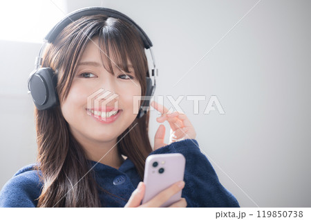 ヘッドフォンをつけて音楽を聴く歌う若い女性のクローズアップのイメージ 119850738