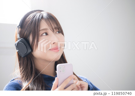 ヘッドフォンをつけて見上げる音楽を聴く歌う若い女性のクローズアップのイメージ　コピースペースあり 119850740