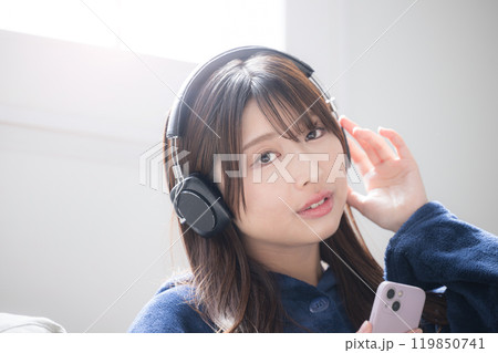 ヘッドフォンをつけて音楽を聴く歌う若い女性のクローズアップのカメラ目線のイメージ　コピースペースあり 119850741