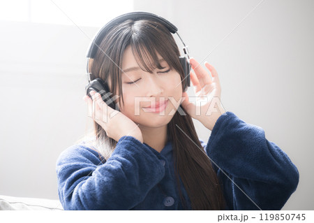 ヘッドフォンをつけて目を閉じる、音楽を聴く歌う若い女性のクローズアップのイメージ コピースペースあり ヘッドフォンをつけて目を閉じる、音楽を聴く歌う若い女性のクローズアップのイメージ コピースペースあり 119850745