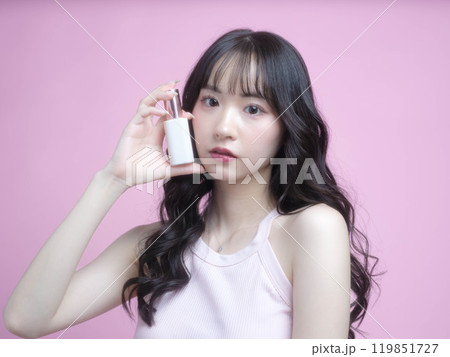 化粧品を持ってメイクアップをする女性 119851727