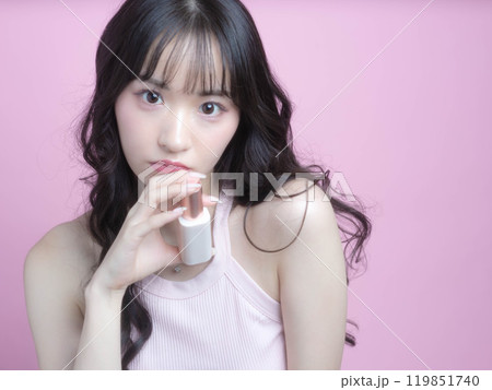 化粧品を持ってメイクアップをする女性 化粧品を持ってメイクアップをする女性 119851740