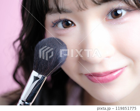 化粧品を持ってメイクアップをする女性 119851775
