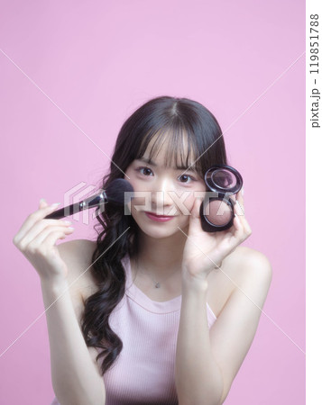 化粧品を持ってメイクアップをする女性 119851788
