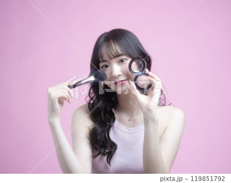 化粧品を持ってメイクアップをする女性 119851792