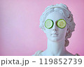 Statue of a Greek goddess with cucumber slices on eyes. Sculpture on spa treatments after bath. Beauty procedures, self-care, art, wellness, cosmetics and beauty salon, relaxation concept 119852739