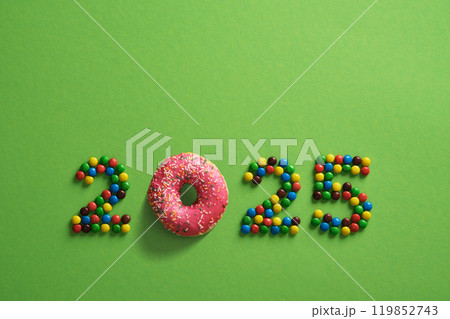 Candy and pink donut figures 2025 on green background. New Year concept 119852743