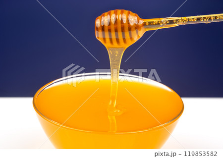 fresh fragrant honey drips from a spoon into a plate on a colored background. fresh fragrant honey drips from a spoon into a plate on a colored background. 119853582