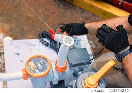 Assembling sand filter system tank and equipment for cleaning water in swimming pools by maintenance worker 119854236