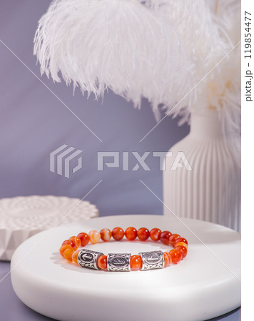 Woman's wrist wearing orange agate bracelet, isolated on white background. 119854477