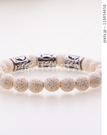 A charming double bracelet in shades of pink, made from natural stone and set against a gray background. The heart charm with cubic zirconia stands out in this close-up top view A charming double bracelet in shades of pink, made from natural stone and set against a gray background. The heart charm with cubic zirconia stands out in this close-up top view 119854658