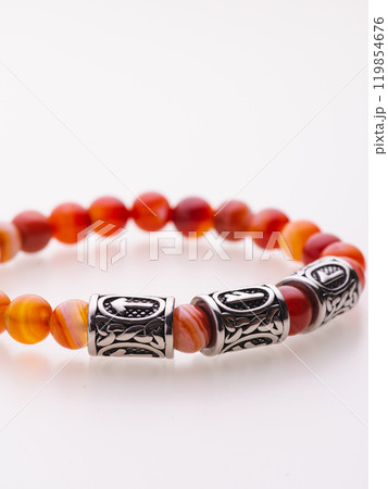 A charming double bracelet in shades of pink, made from natural stone and set against a gray background. The heart charm with cubic zirconia stands out in this close-up top view 119854676