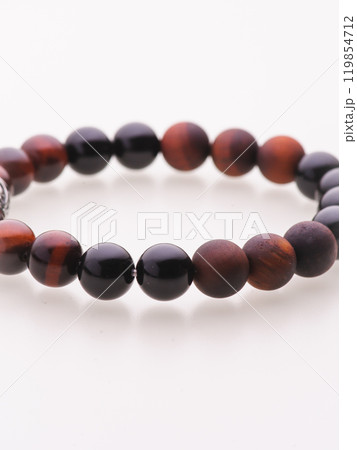 A charming double bracelet in shades of pink, made from natural stone and set against a gray background. The heart charm with cubic zirconia stands out in this close-up top view 119854712