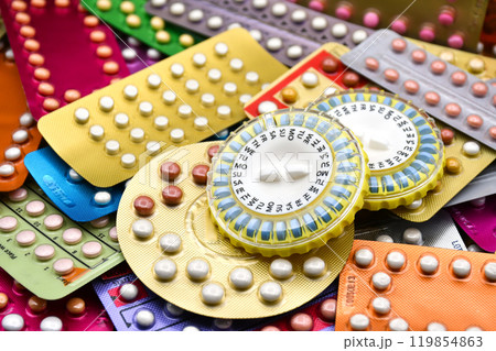 Oral contraceptive pill on pharmacy counter with colorful pills strips background. Oral contraceptive pill on pharmacy counter with colorful pills strips background. 119854863