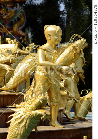 The golden statue of a child holding a fish represents abundance according to ancient Chinese beliefs. The golden statue of a child holding a fish represents abundance according to ancient Chinese beliefs. 119854878