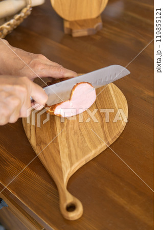 person cutting ham on cutting board 119855121