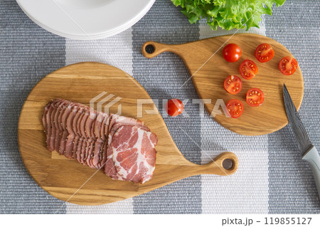 cherry tomatoes and sliced ham on a cutting boards on a table cherry tomatoes and sliced ham on a cutting boards on a table 119855127