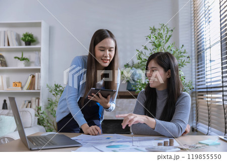 Team of partners Asian business woman discussing project on laptop sitting at table in office. Two colleagues of professional business people working together. Team of partners Asian business woman discussing project on laptop sitting at table in office. Two colleagues of professional business people working together. 119855550