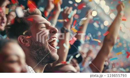 A man is smiling and surrounded by people, with confetti falling around him 119855793