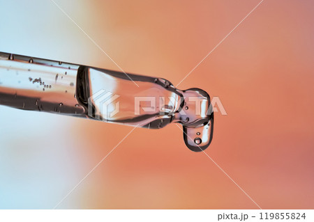 A pipette with facial serum against a sunset background in bright orange tones. A pipette with facial serum against a sunset background in bright orange tones. 119855824