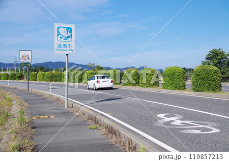 車高を適度に下げた白色の乗用車が鳥取県境港市の米子鬼太郎空港沿いのメロディー道路を走る光景 119857213