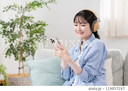 リビングで音楽を聴く若い女性 リビングで音楽を聴く若い女性 119857287