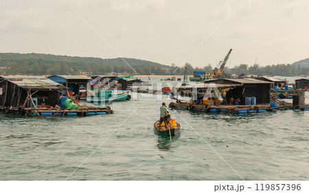 Vietnam, houseboats on the water that are fish farms, there is an excavator on one of them 119857396