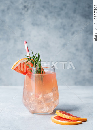Grapefruit lemonade with rosemary and ice in a glass on a blue background with fresh citrus slices. Grapefruit lemonade with rosemary and ice in a glass on a blue background with fresh citrus slices. 119857506