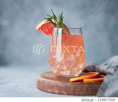 Homemade grapefruit lemonade with rosemary and ice in a glass on a wooden board on light background Homemade grapefruit lemonade with rosemary and ice in a glass on a wooden board on light background 119857509