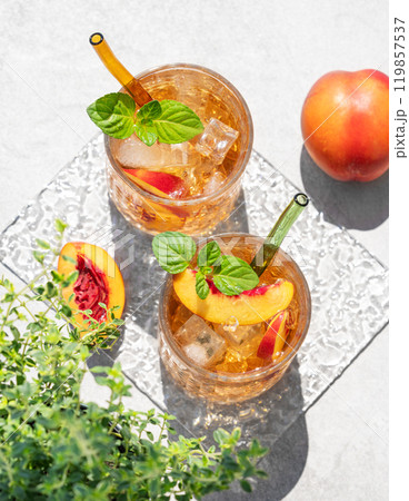 Peach lemonade with ice and mint on a concrete background. Fresh iced tea in glasses with shadow 119857537
