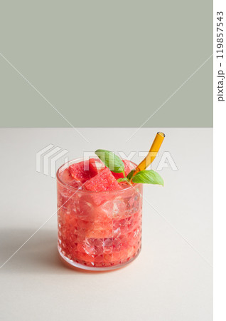 Refreshing watermelon cocktail in glass with basil and ice on a white and green background. Refreshing watermelon cocktail in glass with basil and ice on a white and green background. 119857543