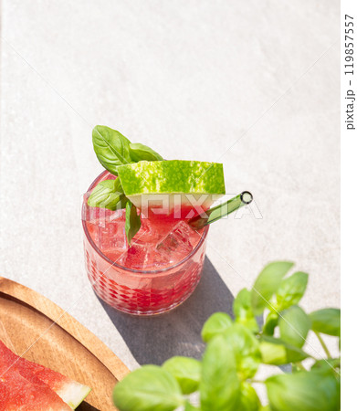 Glass of refreshing watermelon cocktail with basil and ice with fruit slices and fresh herb  119857557