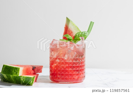 Glass of refreshing watermelon smoothie with basil, ice on white marble background Glass of refreshing watermelon smoothie with basil, ice on white marble background 119857561