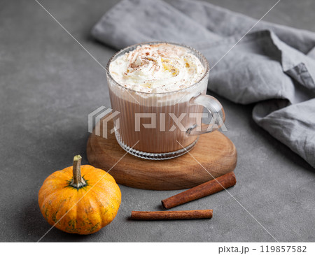 Spice latte with whipped cream in glass cup on wooden board on dark background with pumpkin Spice latte with whipped cream in glass cup on wooden board on dark background with pumpkin 119857582