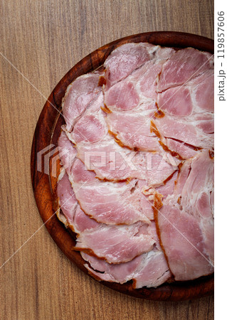 sliced pork neck, boiled and smoked, smoked pork neck, sliced, on a wooden chopping board, close-up, 119857606