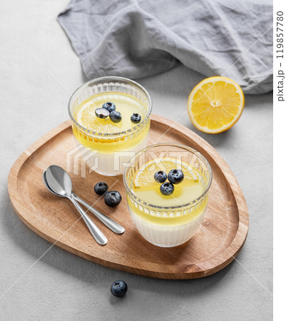 lemon panna cotta with blueberries in two glasses on a light background with berries 119857780