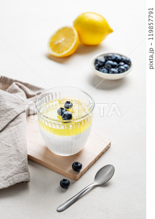 lemon panna cotta with blueberries in  glass on a light background with fruits and spoon. 119857791