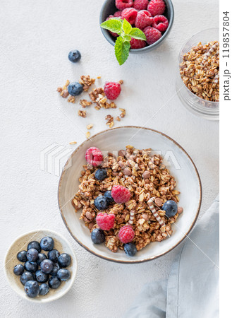 Flat lay of granola, raspberries and blueberries in a bowl on a light background  119857804