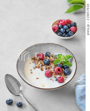 Granola with greek yogurt, raspberries and blueberries in a bowl on a white background 119857816