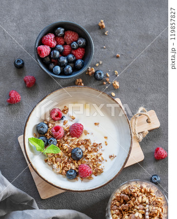Granola with greek yogurt, raspberries and blueberries in a bowl on a wooden board 119857827