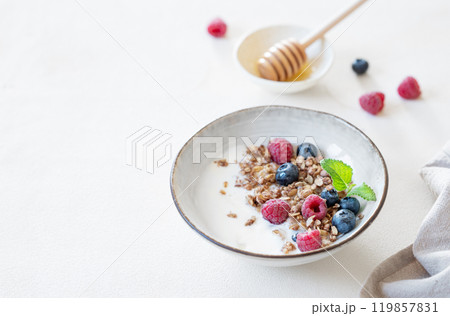 Granola with greek yogurt, raspberries, blueberries and honey in a bowl on a white background Granola with greek yogurt, raspberries, blueberries and honey in a bowl on a white background 119857831