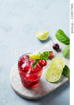 Cherry-lime mojito cocktail with mint, lime and ice on a marble board on a light background. Cherry-lime mojito cocktail with mint, lime and ice on a marble board on a light background. 119857908