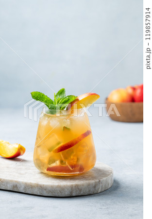 Refreshing peach cocktail, lemonade or iced tea on a marble board on a light background. 119857914