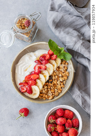 Greek yogurt with muesli, strawberry and banana in a bowl on a blue background 119857934