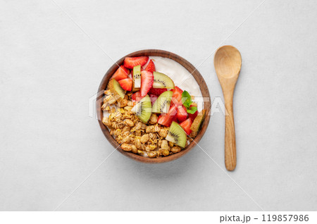 Natural yogurt with granola, kiwi and strawberries in a wooden bowl on a light background with spoon 119857986