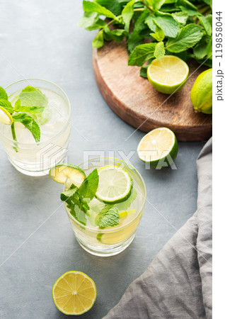 Two glasses lime mojito with mint and ice. Refreshing citrus cocktail on a light background. Two glasses lime mojito with mint and ice. Refreshing citrus cocktail on a light background. 119858044