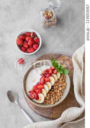Greek yogurt with muesli, strawberry and banana in a bowl on a wooden board on a  light background  119858067