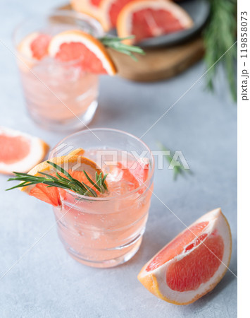 Two glasses grapefruit lemonade drink with rosemary and ice on a blue background  119858073
